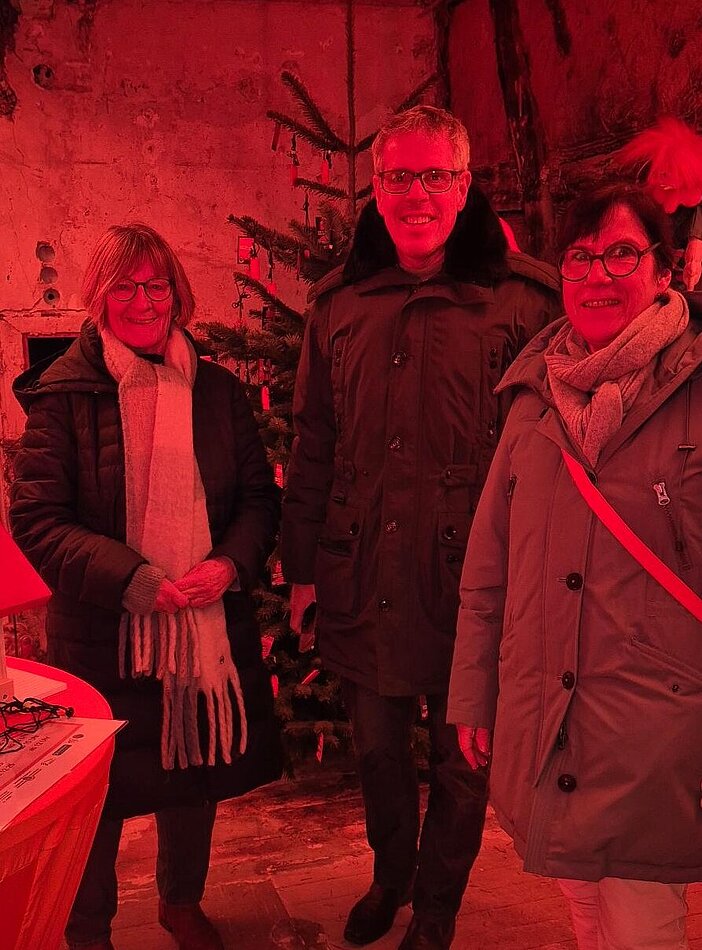 Blick in das Haus mit Personen vor einem geschmückten Tannenbaum