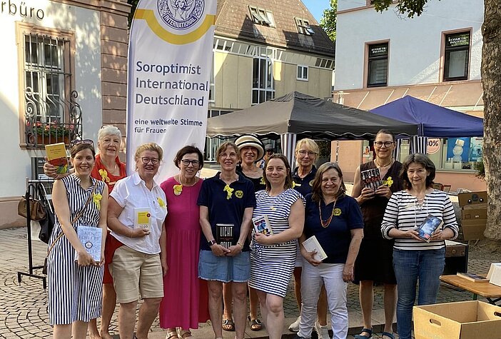 Gruppe von Frauen mit Büchern in den Händen vor einer Flagge von Soroptimist International Deutschland